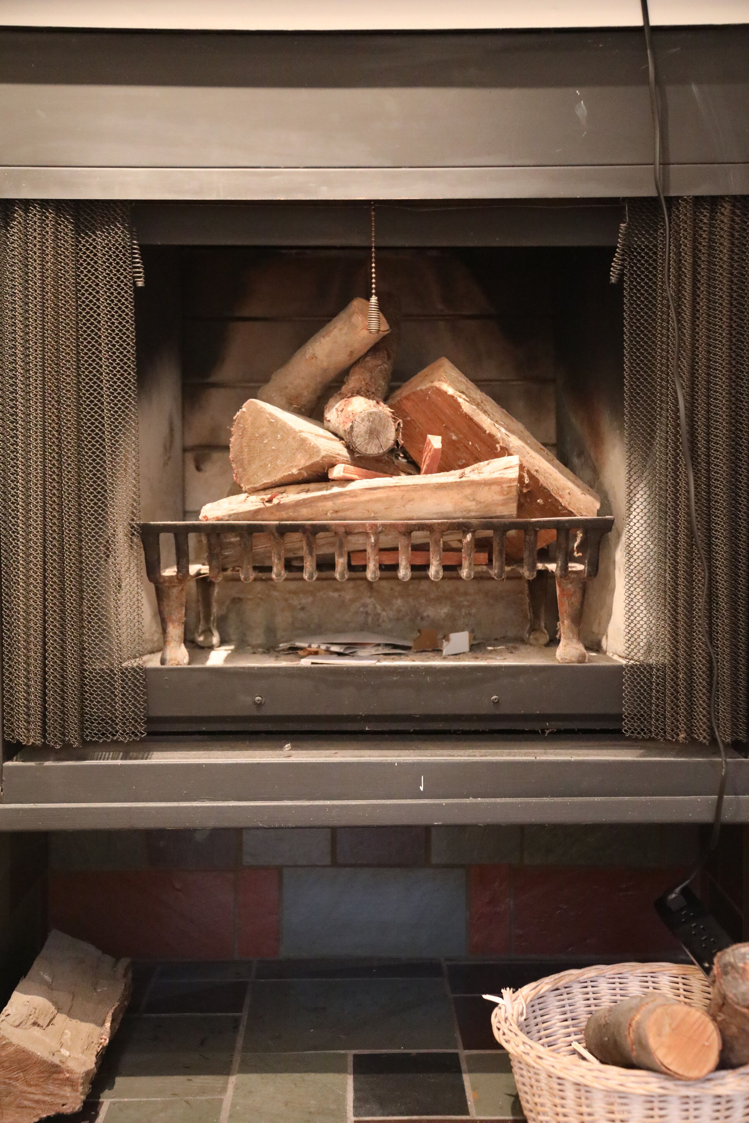 Una chimenea con rejilla metálica y leña.