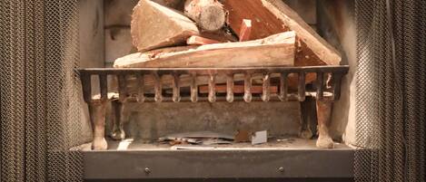 Una chimenea con rejilla metálica y leña.