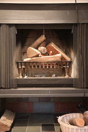 A fireplace with a metal grate and logs. - Staycation at Upstate NY: Fenced Dog Yard & Peaceful Family Escape w/Pool & WIFI (Saugerties)