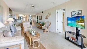 A spacious living room with a sofa, armchairs, a coffee table, and a television.