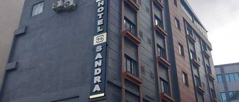 Un immeuble abritant un hôtel à plusieurs étages, sur lequel on peut voir une enseigne bien visible indiquant « HÔTEL SANDRA ».