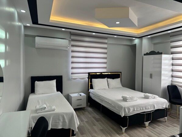 A modern hotel room with two beds, a wardrobe, a desk, and a chair. - Hotel Sandra (Sanliurfa)