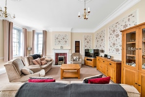 A living room with a sofa set, a fireplace, a television, and a cabinet.