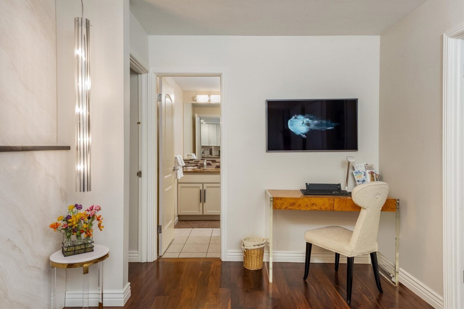 Une cuisine moderne dotée d’un îlot central, d’un coin repas avec une chaise et d’un téléviseur fixé au mur.