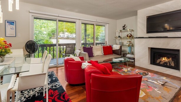 A modern living room with a sofa, red chairs, a glass coffee table, and a fireplace. - Cozy and Convenient 2BR in Vail Village - Walk to Gondola One (Vail)