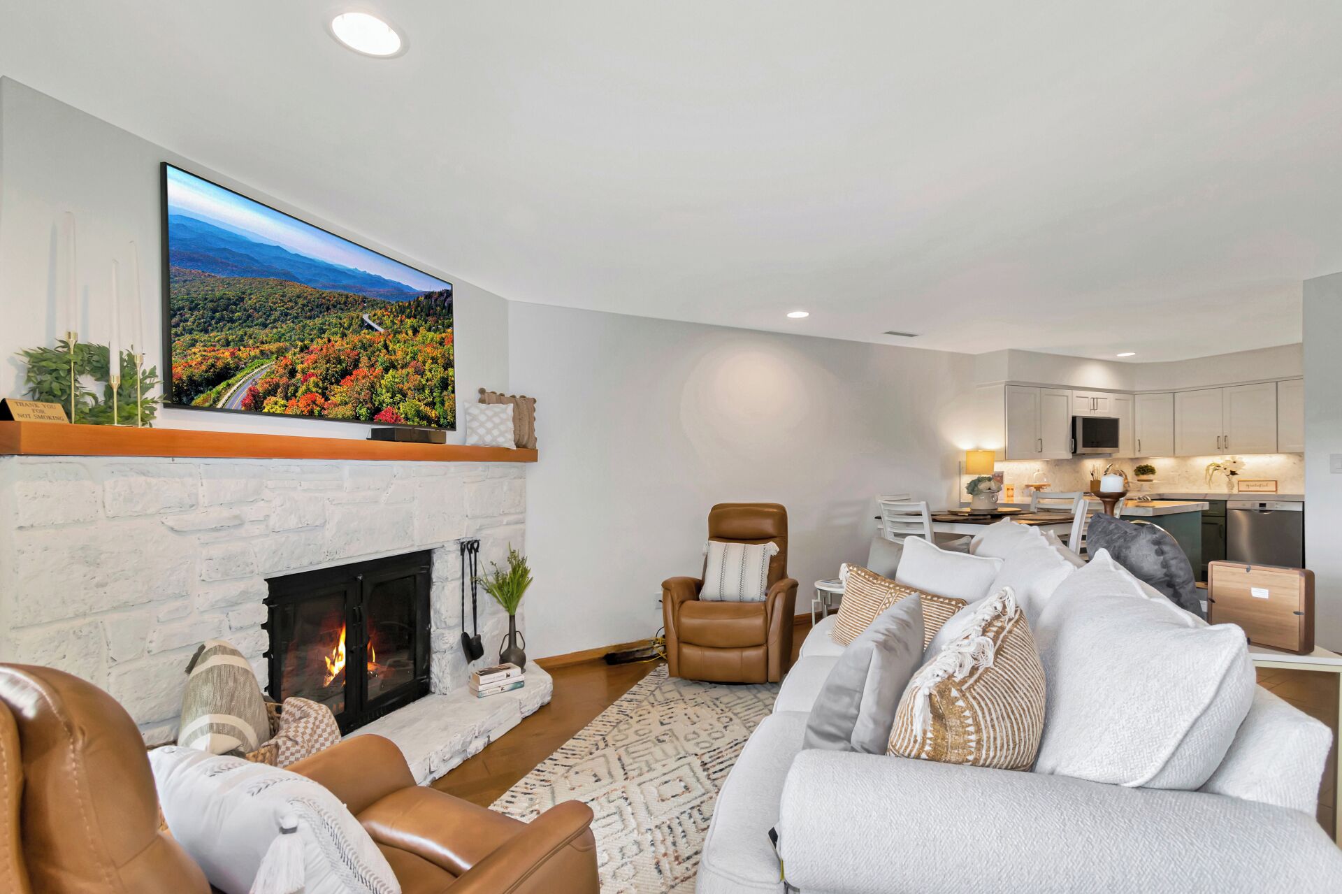 A modern living room with a fireplace, a large flat-screen TV, and a cozy seating area.
