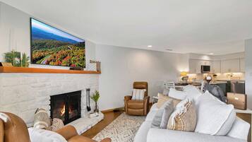 A modern living room with a fireplace, a large flat-screen TV, and a cozy seating area.