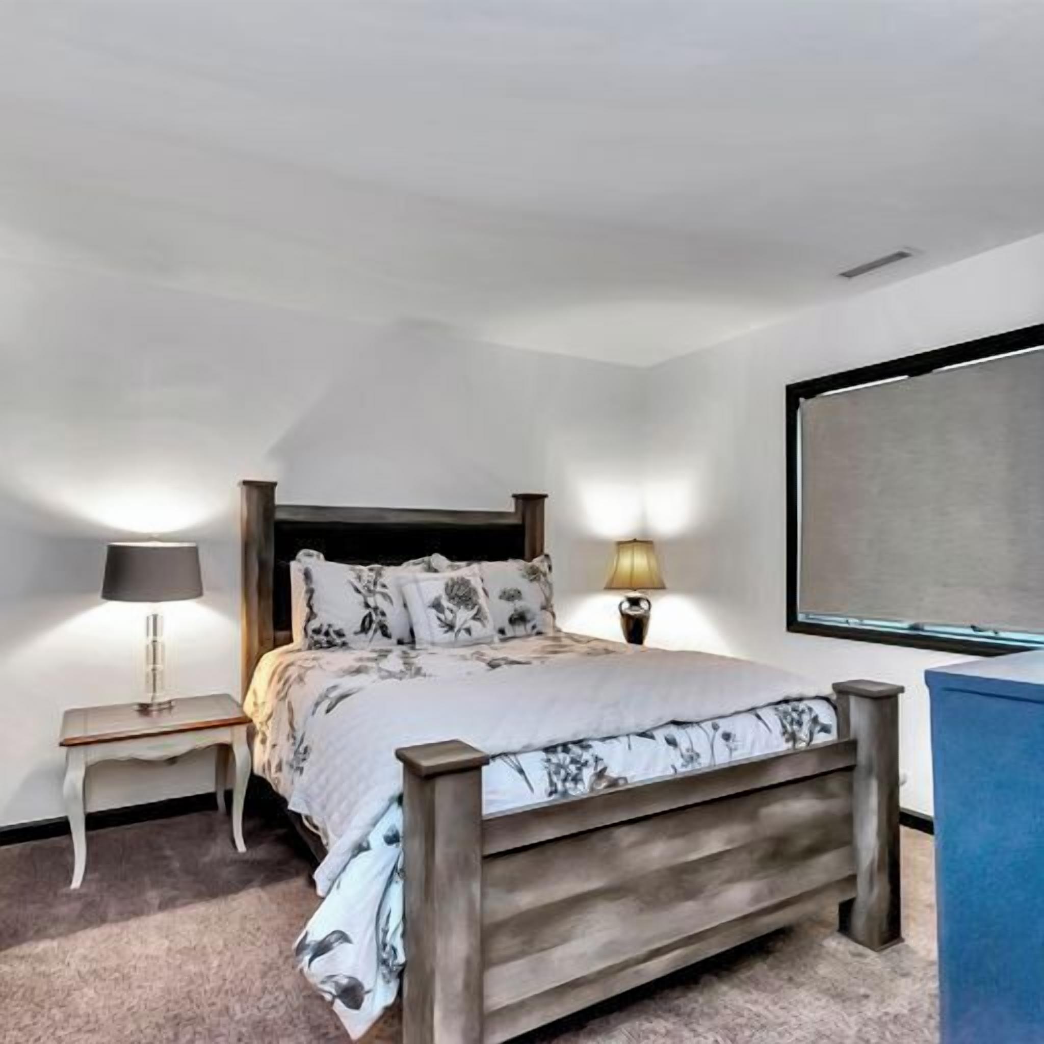 Une chambre à coucher avec un lit, des tables de chevet, une lampe et un téléviseur.