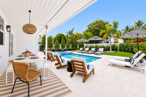 An outdoor pool area with lounge chairs and a dining table.