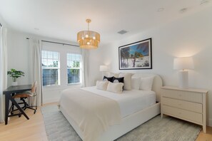 Quarto com cama, mesas de cabeceira, escrivaninha e uma cadeira.