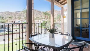 A balcony with a round table and chairs, a potted plant, and a view of a residential area with houses and mountains. - Legacy Villas- 1 BR Suite with separate Living Room,Patio, Views,Sleeps 4-064225 (La Quinta)