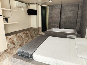 Une salle de bain moderne équipée d’une baignoire, d’une douche, de toilettes et d’un téléviseur fixé au mur.