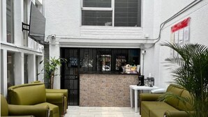 A courtyard with a seating area, a small bar, and a view of the street. - Hotel Villanueva Comfort (Medellín)