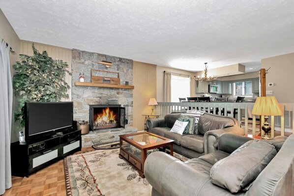 A living room with a stone fireplace, a television, a sofa, and a coffee table.
