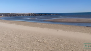 A sandy beach with a rocky breakwater and calm sea.