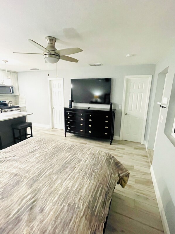A bedroom with a bed, a dresser, a television, and a ceiling fan.
