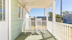 A porch with a white railing and a wooden bench.
