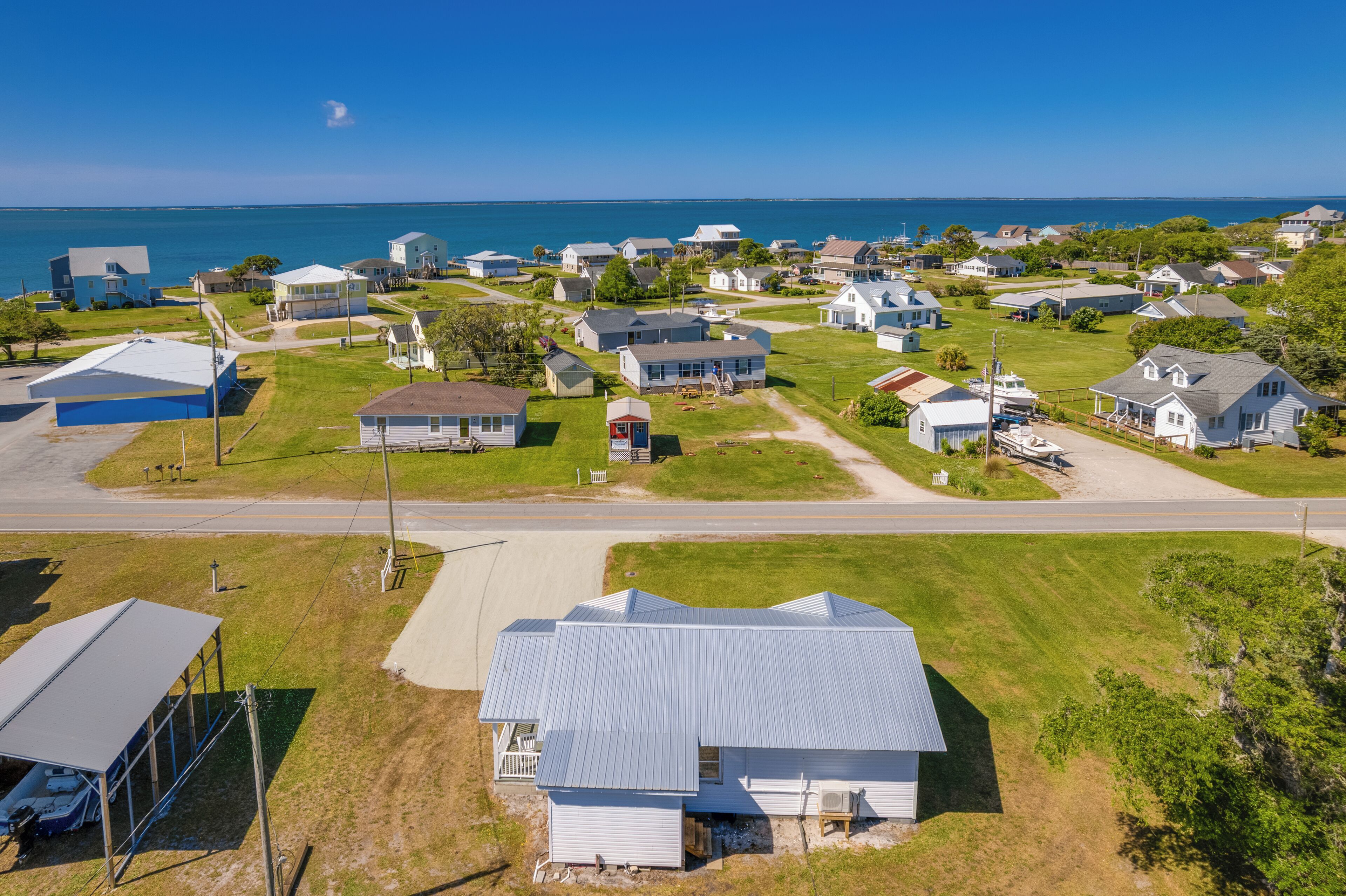 A residential area with houses, a road, and a body of water in the background.