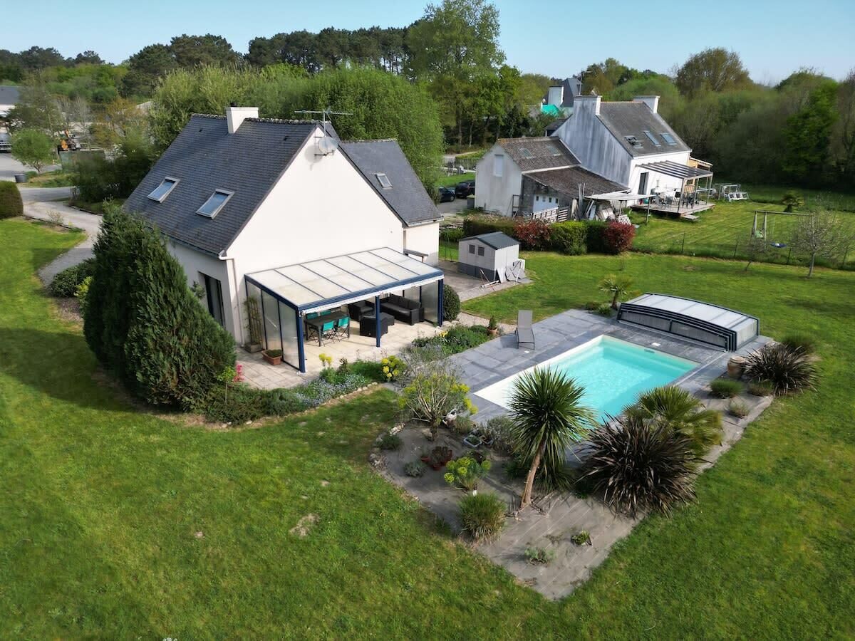 Ein Wohnhaus mit Swimmingpool, einer überdachten Terrasse und einem gepflegten Rasen.