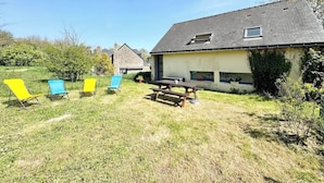 A house with a sloped roof, a small window, and a picnic table in the yard.
