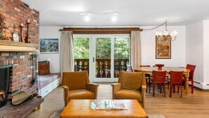 Ένα άνετο σαλόνι με τζάκι, ευρύχωρους καναπέδες, μια τραπεζαρία και θέα που διακρίνεται μέσα από μεγάλες γυάλινες πόρτες.
