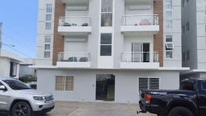 A multi-story residential building with balconies, a garage, and parked vehicles. - Stay at luxurious exclusive condo 10 minute walk from caleta beach  (La Romana)