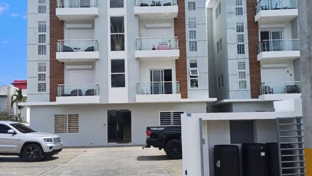 A multi-story residential building with balconies, a garage, and a parking area. - Stay at luxurious exclusive condo 10 minute walk from caleta beach  (La Romana)