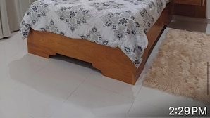 A bedroom with a wooden bed, a nightstand, a fluffy rug, and a ceiling fan. - Stay at luxurious exclusive condo 10 minute walk from caleta beach  (La Romana)