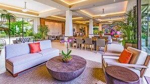 Eine geräumige Lobby mit einer Couch, Sesseln, einem Couchtisch und einem Essbereich.
