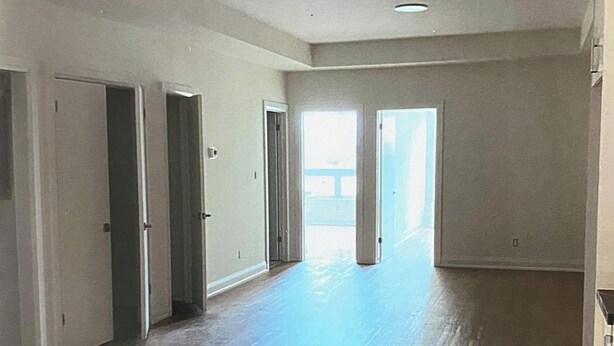 A spacious room with hardwood flooring, white walls, and a large window. - New 2 bedroom apartment in Toronto 
782 St. Clair ave.west (Toronto)
