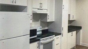 A kitchen with white cabinets, a black countertop, and a wooden floor. - New 2 bedroom apartment in Toronto 
782 St. Clair ave.west (Toronto)
