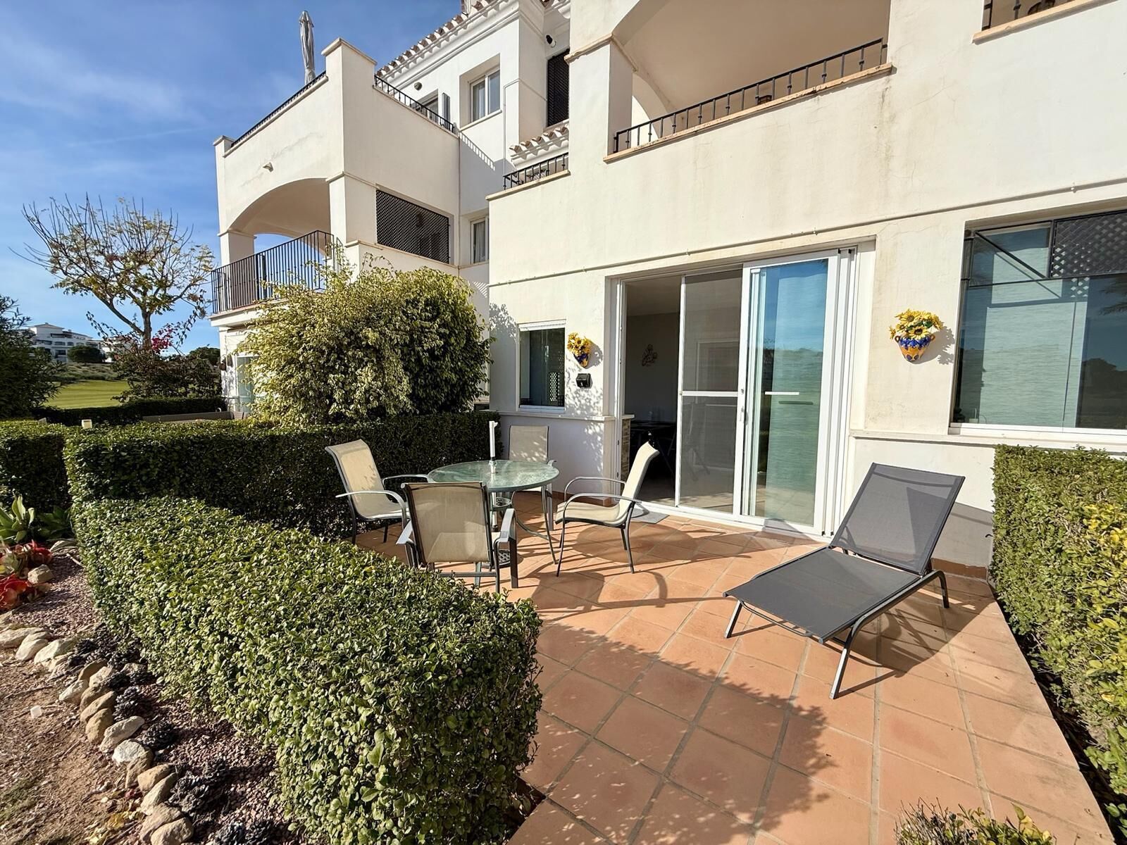 Un immeuble résidentiel doté d’un patio, d’une porte vitrée donnant sur un balcon et d’une petite table avec des chaises.