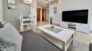 Un saló modern amb sofà, taula de centre, televisió i zona de menjador.
