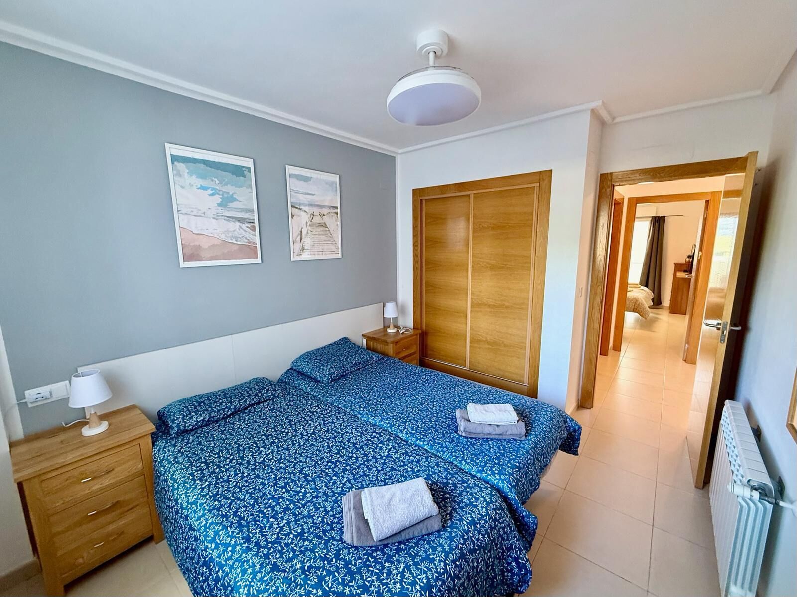 Une chambre à coucher comprenant un lit, une armoire en bois, des tables de chevet et un luminaire au plafond.