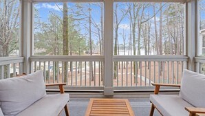 A room with a large window, a wooden bench, and two white sofas.