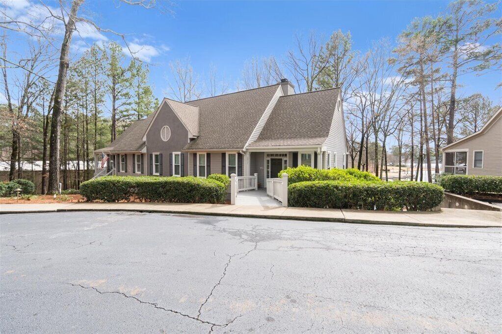 A two-story residential building with a gabled roof, a front porch, and a driveway.