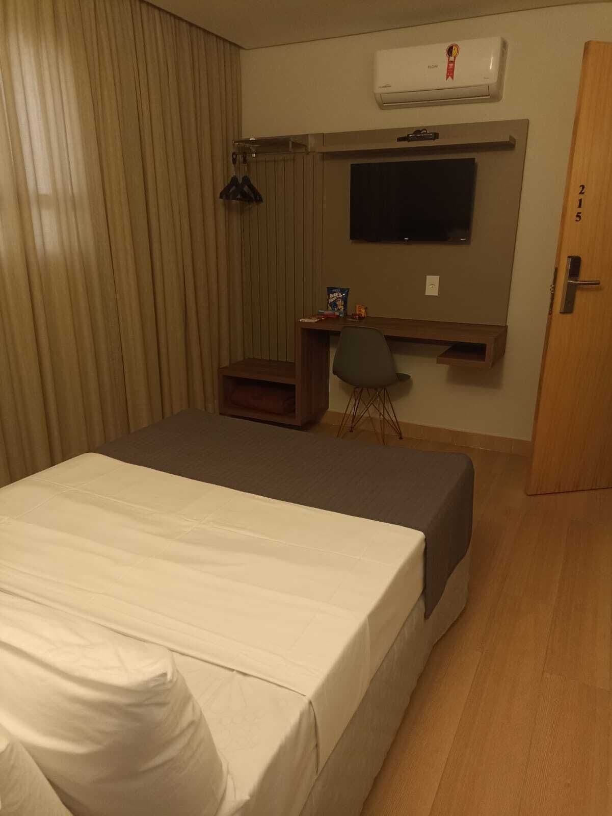Habitación de hotel con cama, escritorio, silla, aire acondicionado y televisión.