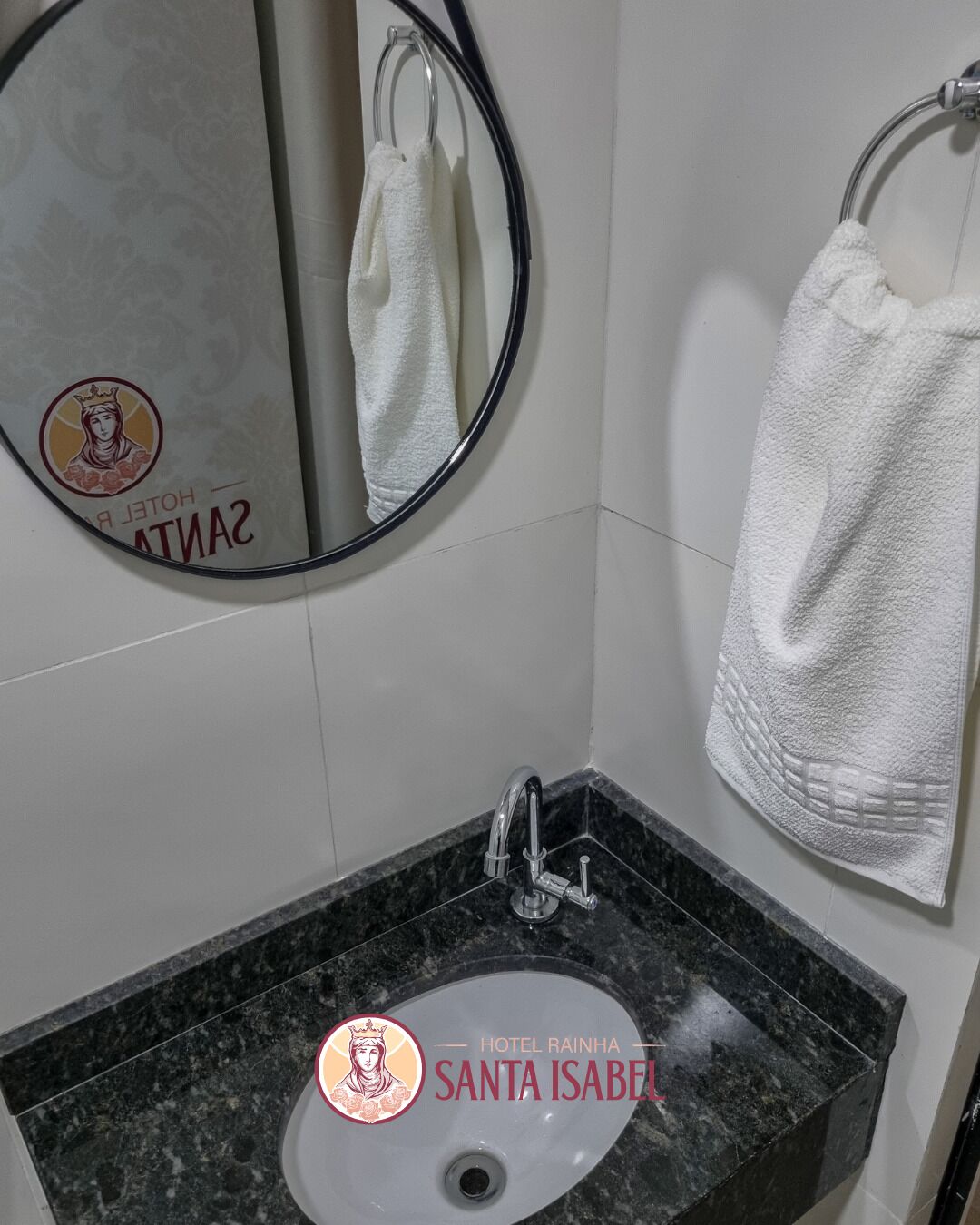 A bathroom with a marble sink, a round mirror, and a towel rack.