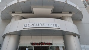 The exterior of the Mercure Hotel, featuring a modern design with a curved facade and a prominent entrance.