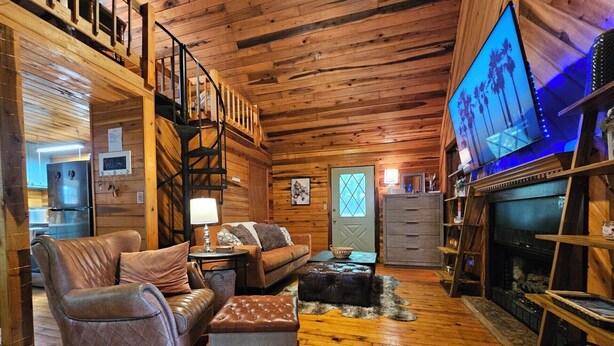A cozy cabin interior with a wooden interior, a fireplace, a television, and a staircase. - White-Tail Nook Blue Ridge Cabin! (Blue Ridge)