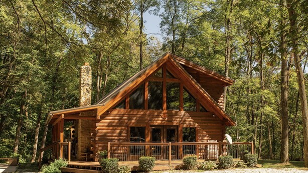 A log cabin with a stone chimney, large windows, and a porch with railings. - Sugar Creek Cabin w/ Nordic spa bordering 2 state parks! (Waveland)