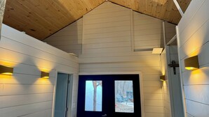 A wooden interior with a sloped ceiling, white walls, and two illuminated wall sconces. - Sugar Creek Cabin w/ Nordic spa bordering 2 state parks! (Waveland)