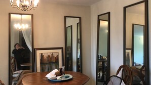 A dining area with a round table, chairs, a chandelier, and framed artwork.