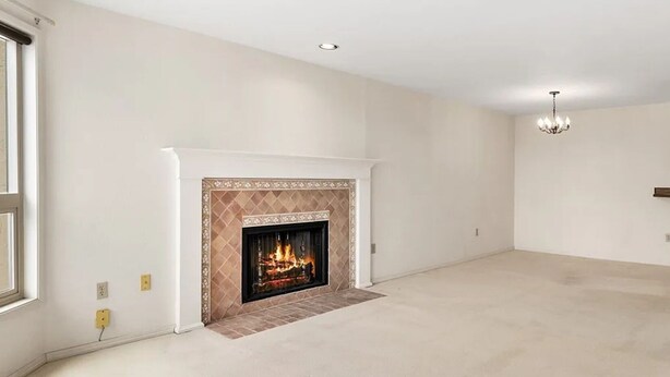 A spacious room with a fireplace, a chandelier, and a large window.