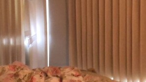 A room with a bed, curtains, and a window with blinds.