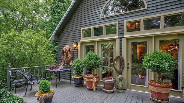 Een houten terras met plantenpotten, een bank en een tafel.