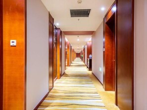 A hotel corridor with wooden doors, a patterned carpet, and a ceiling vent. - Xiangxuehai Hotel (Suzhou)