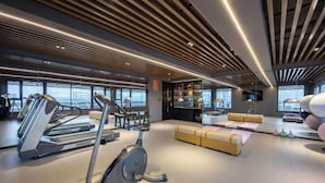 A modern gym with treadmills, an elliptical, and a weight bench. - Xiangxuehai Hotel (Suzhou)