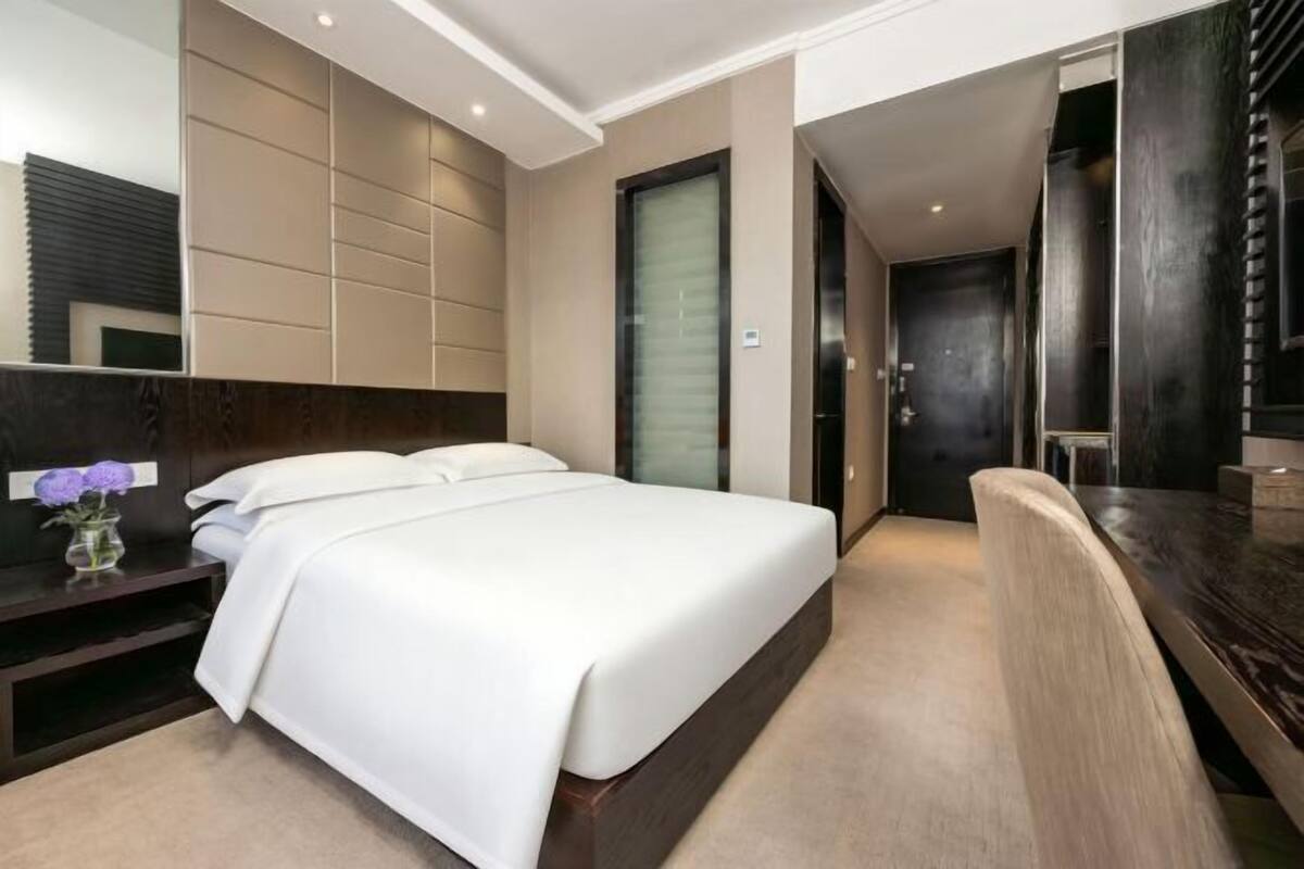 Moderni hotellihuone, jossa on suuri sänky, työpöytä ja peili.