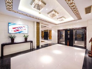 A hotel lobby with a reception desk, a large digital screen, and a modern chandelier. - Xiangxuehai Hotel (Suzhou)
